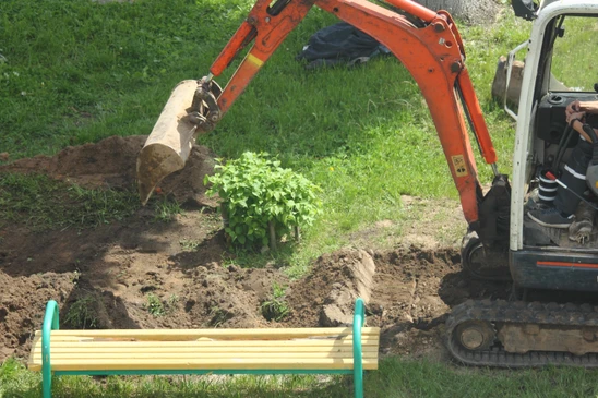 Chantier extérieur avec pelleteuse compacte orange en action, opérateur aux commandes creusant le sol