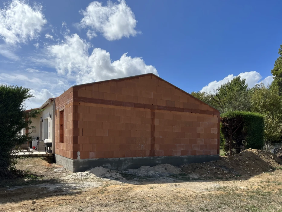 Construction d'une maison individuelle en cours, murs en briques de terre cuite montés sur fondations béton