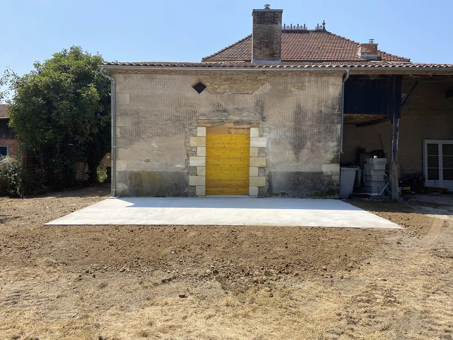 Chantier de rénovation d'une maison ancienne en pierre avec porte jaune restaurée