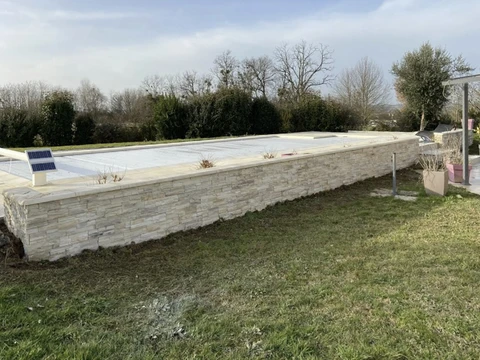 Chantier extérieur de construction de piscine en cours, structure en parpaings avec margelles en pierre naturelle beige