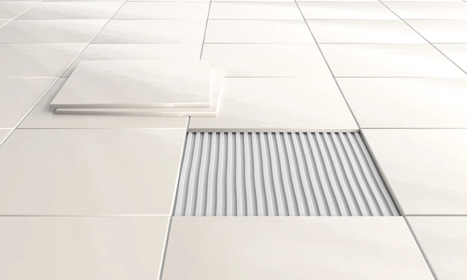 Artisan carreleur appliquant de la colle sur un carreau hexagonal blanc avec une spatule crantée